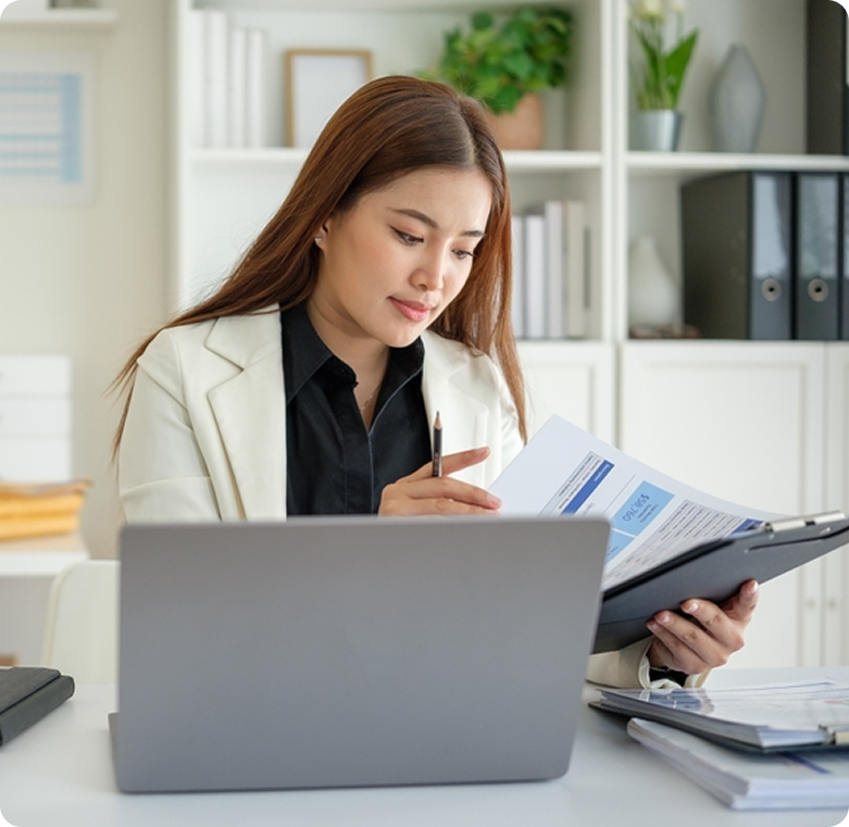 Payroll specialist reviewing documents with a laptop open on the desk